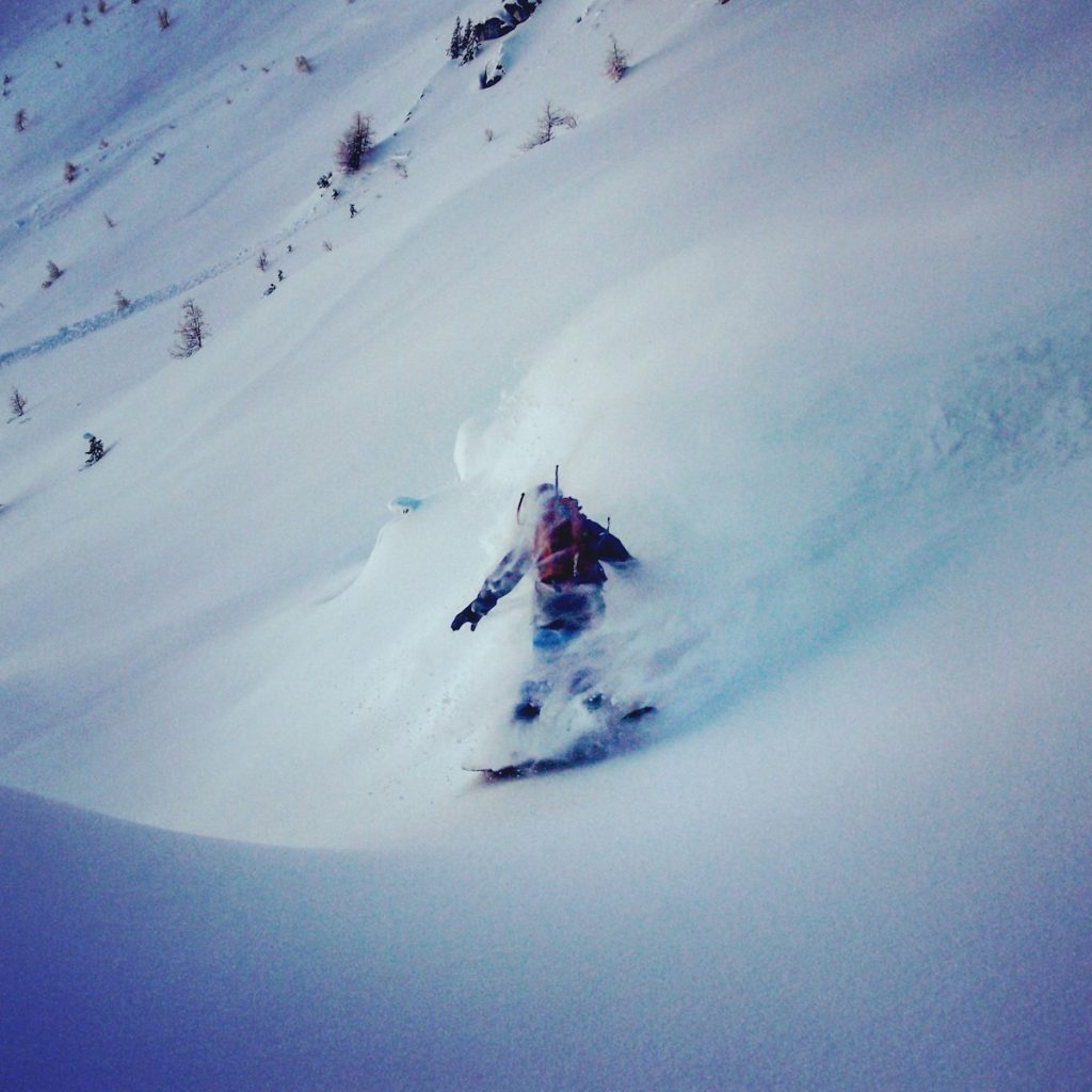 person in red jacket and black pants on snow covered mountain during daytime