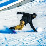 a man riding a snowboard down a snow covered slope